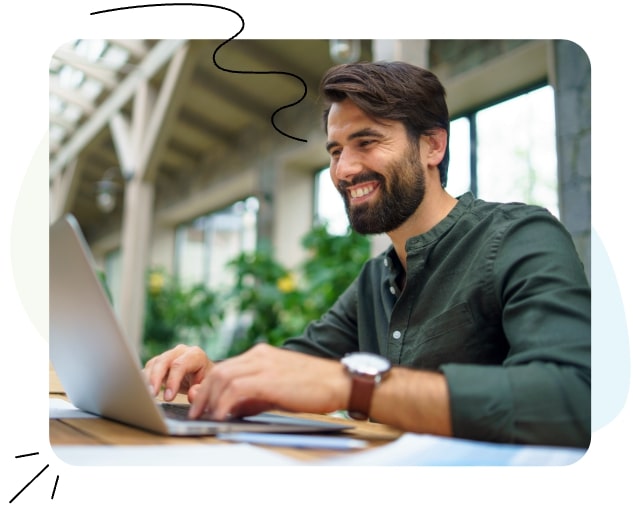 Ein Mann sitzt an einem Schreibtisch und arbeitet an einem Laptop.