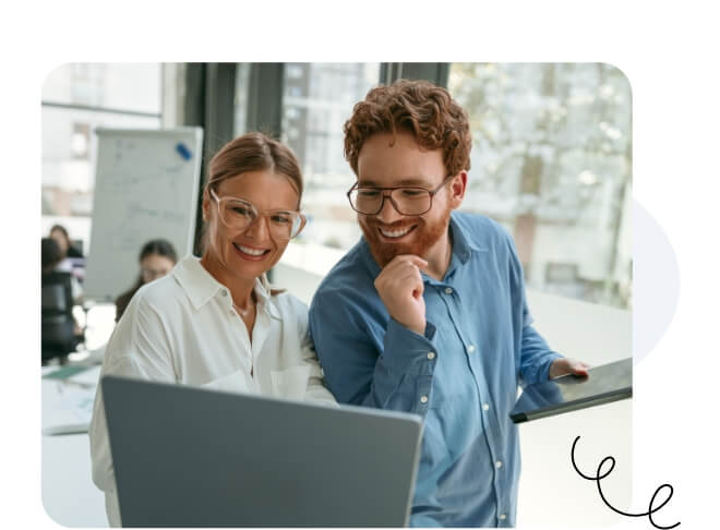 Ein glücklicher Mann und eine glückliche Frau mit Brille lächeln am selben Laptop entlang.