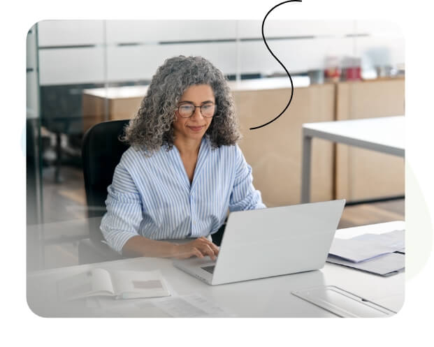 Eine glückliche Frau schaut auf ihren Laptop.