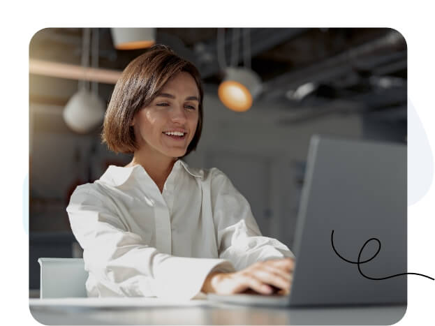 Eine Frau konzentriert sich in einer modernen Büroumgebung auf ihren Laptop-Bildschirm.